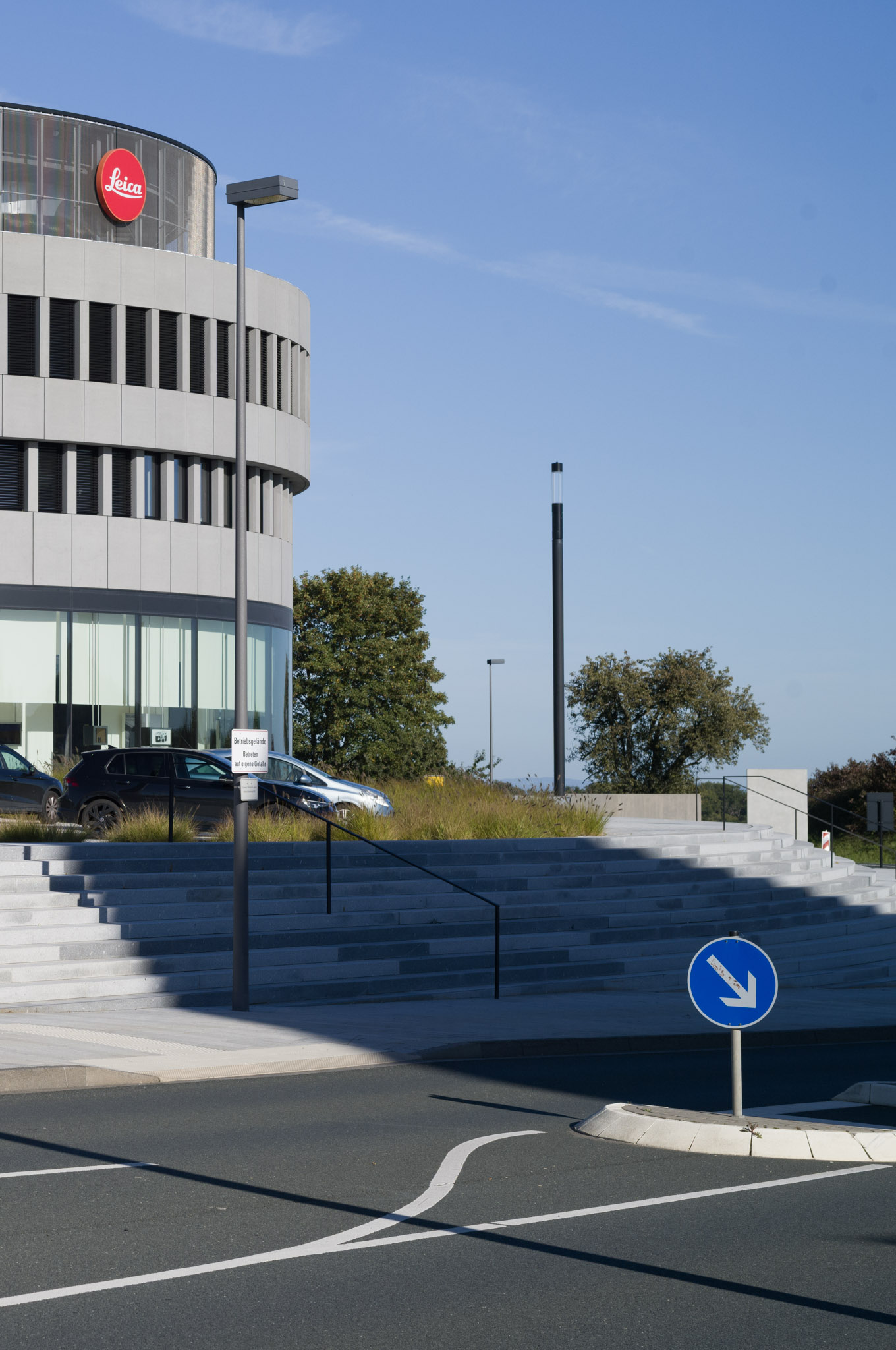 Curved Leica building with glass facade and steps leading to the entrance.