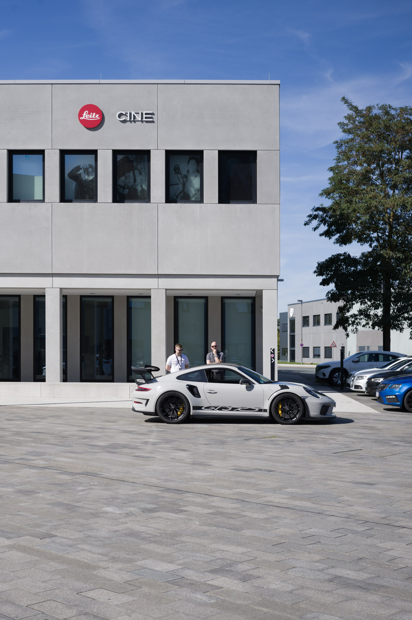 Leitz Cine building with a grey Porsche 911 GT3 RS parked in front.