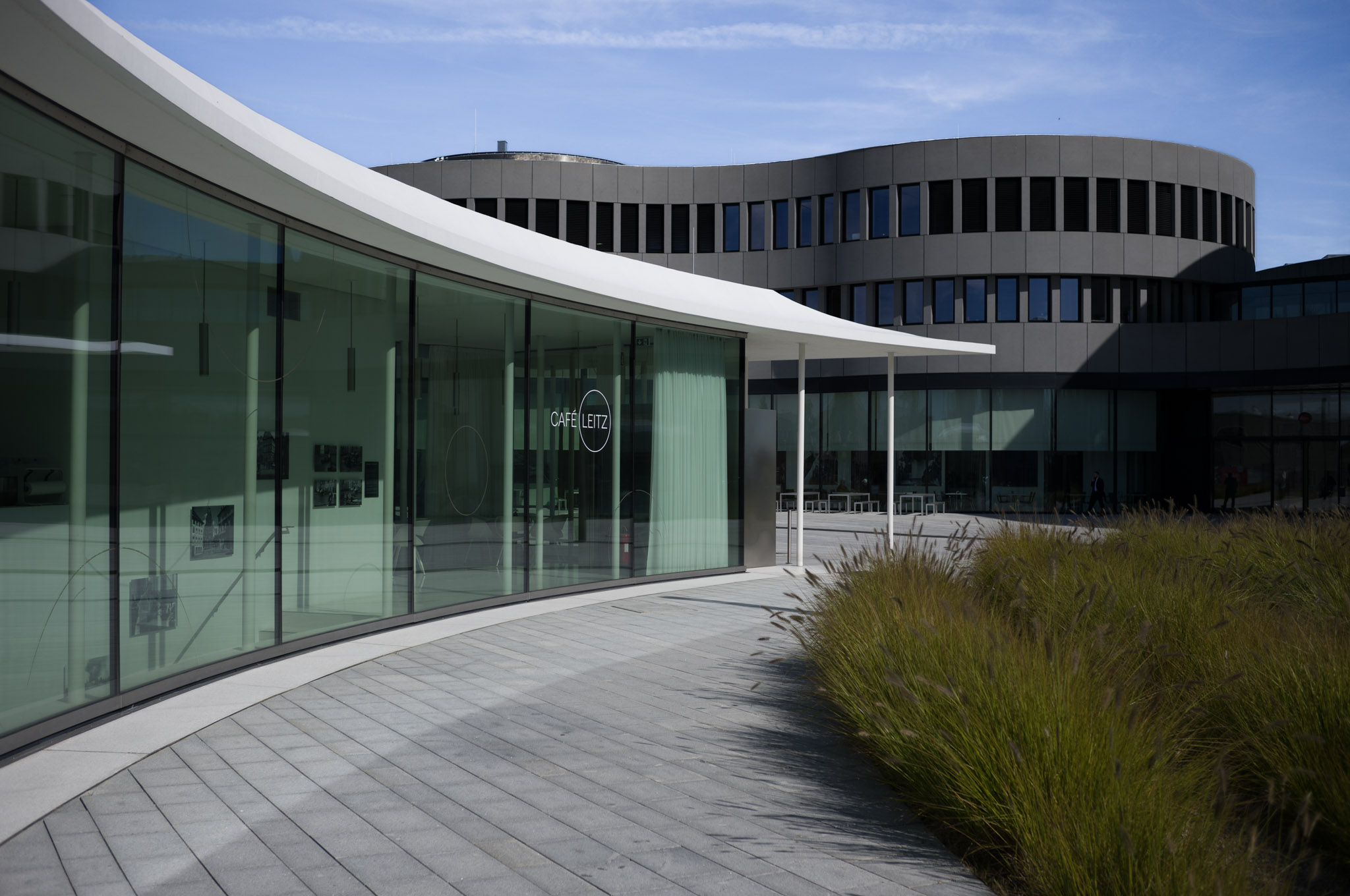 Glass-walled Café Leitz with modern architecture and landscaped walkway.