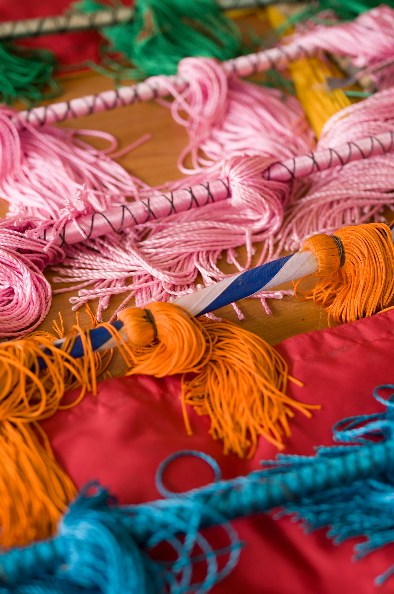 Pink, orange, and teal opera costume tassels and fringe laid out on red fabric.